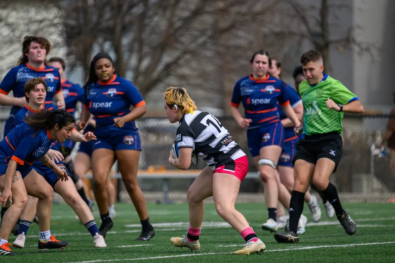 A Women's+ Lions player carries into contact against a side in blue