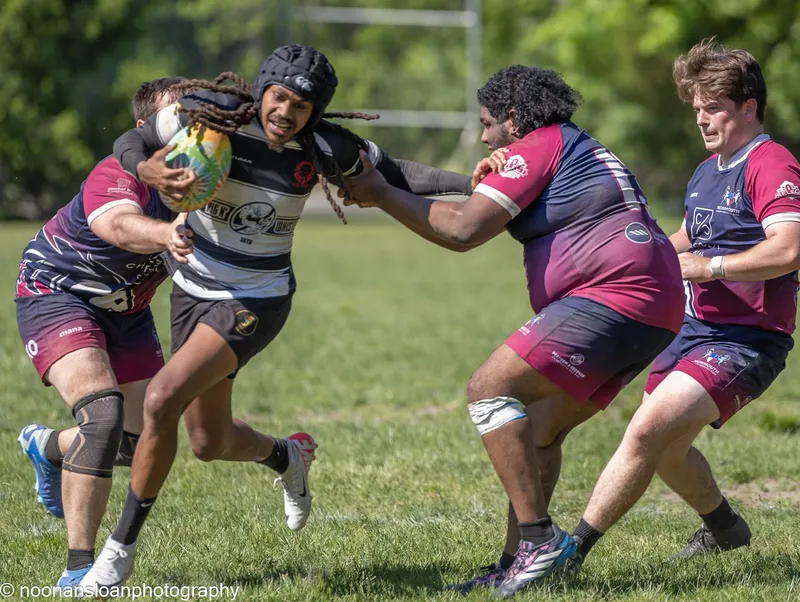 A Lions ball carrier fends off two defenders in maroon