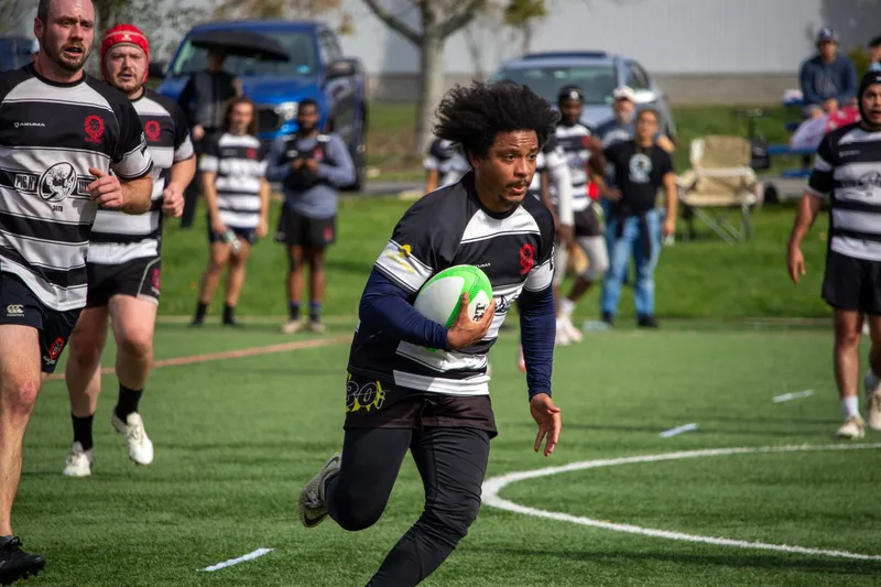 A Lions player breaks into open space with the ball, supporters watching from the sideline