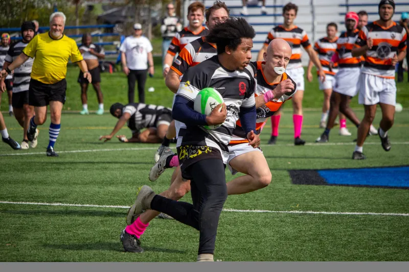 A Lions winger sprints clear with the ball, a side in orange hoops chasing