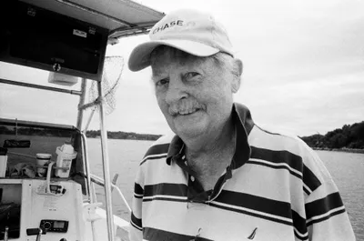 Alan Whelan, the club's founder, in a cap at the helm of a boat