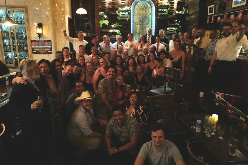 Club members packed into a bar for the 35th anniversary celebration, one raising a fist at the back