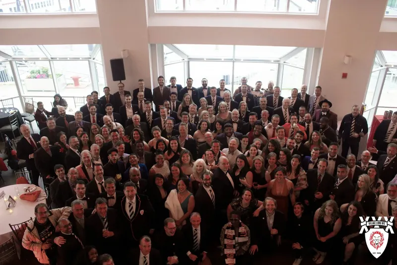 More than a hundred members in black tie at the 30th anniversary celebration, gathered under the windows of a waterfront venue