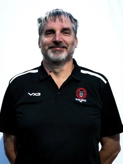 Shay Fitzpatrick, smiling, in a black Village Lions polo shirt
